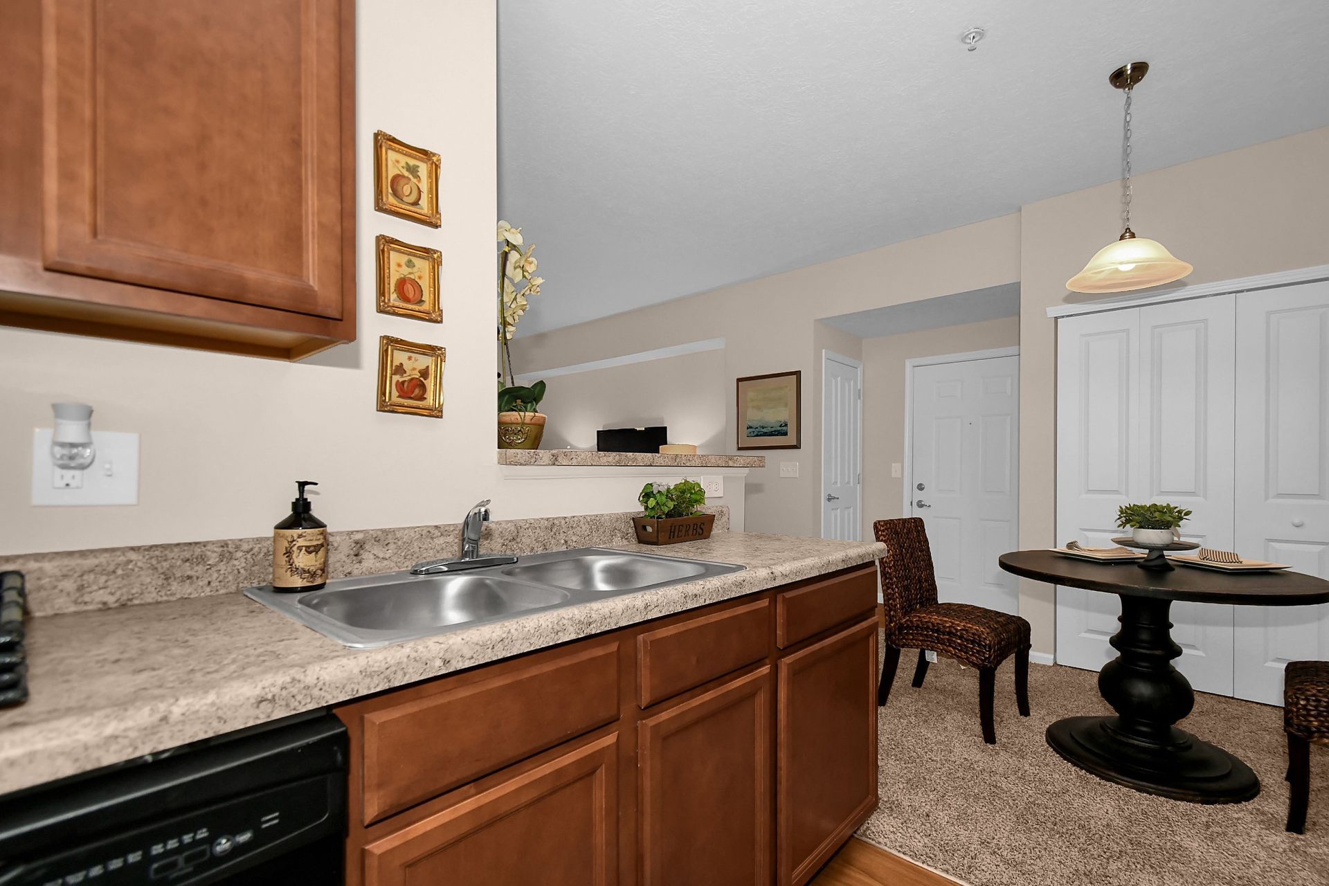 Kitchen with wood cabinets, granite countertop, sink, and a small dining table in an open living area
