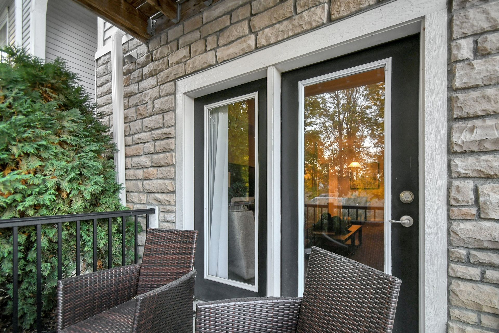 Balcony with wicker chairs beside glass double doors and a brick exterior wall