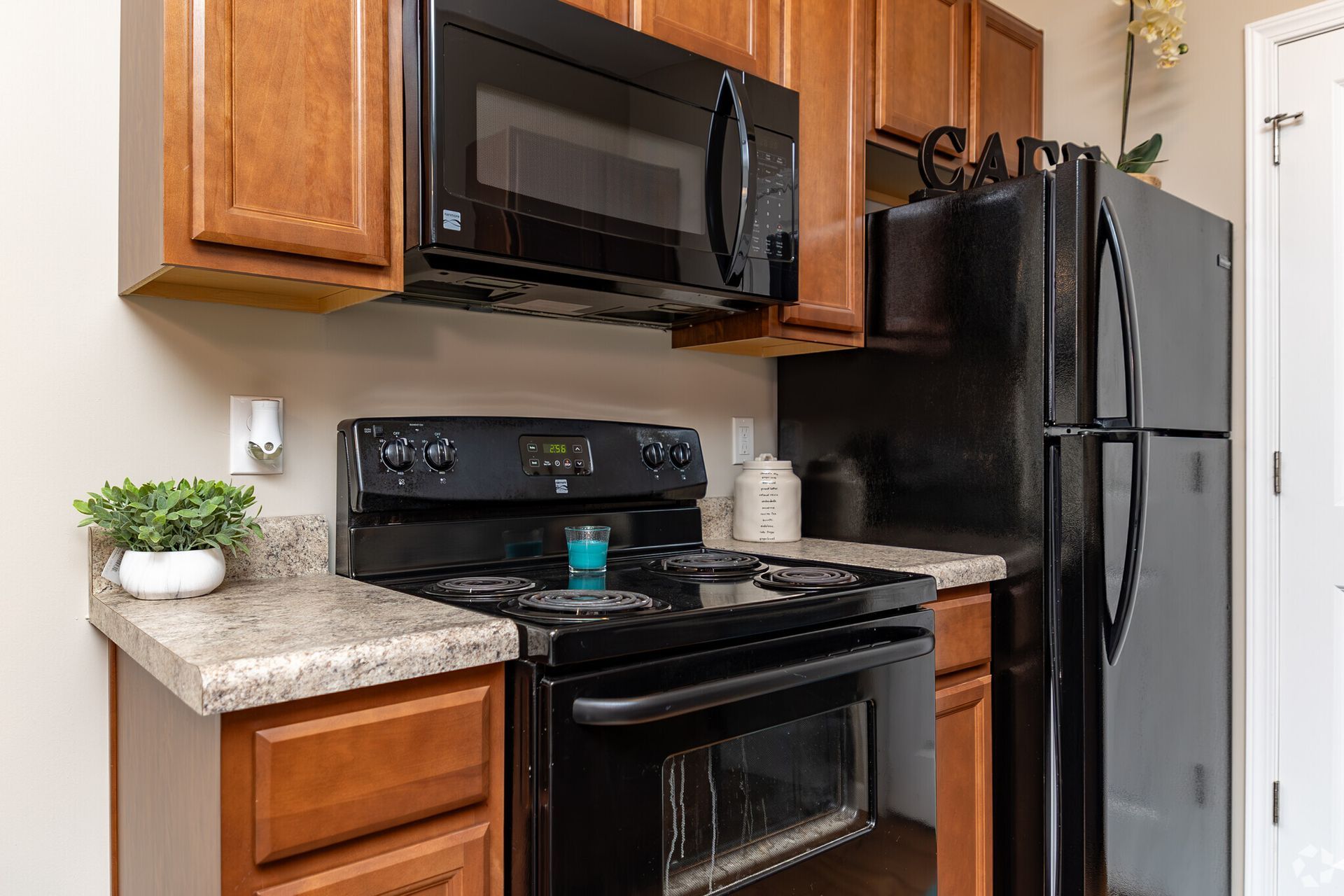 Small kitchen with black appliances, wood cabinets, and granite countertops.
