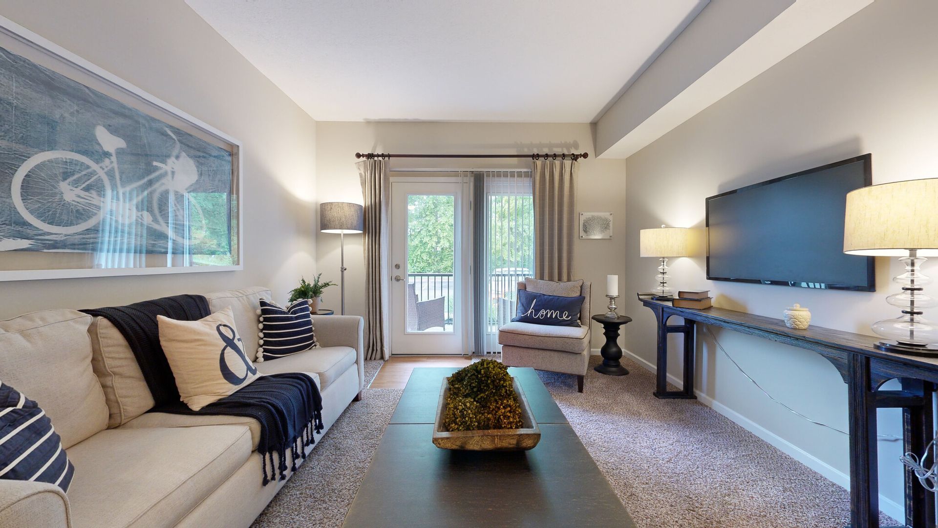 Bright modern living room with sofa, coffee table, console table, and sliding glass doors