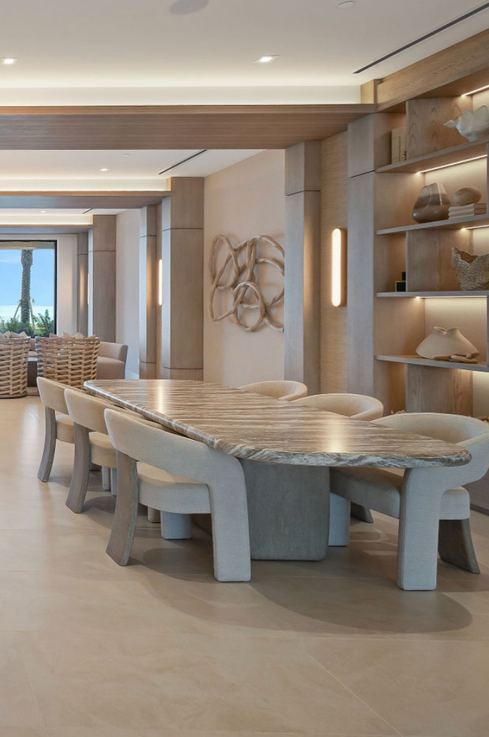 Aqualina in The Bahamas. Dining room with a stone table and chairs, neutral tones, and built-in shelves.