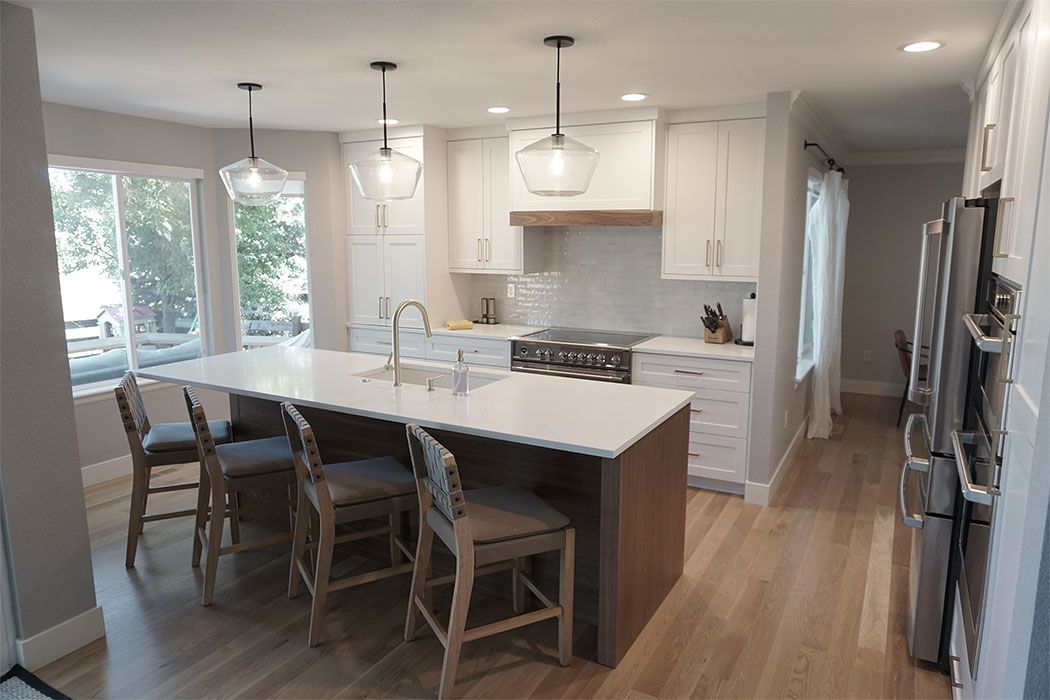 A kitchen with white cabinets , white counter tops , and a large island.