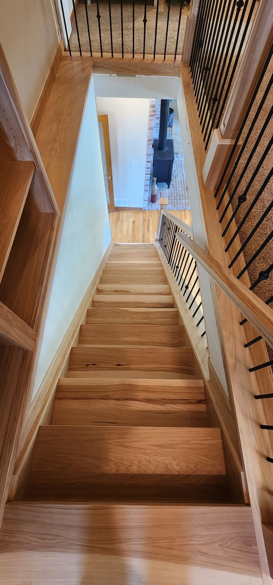 Wooden staircase with dark railing and patterned runner in a home interior