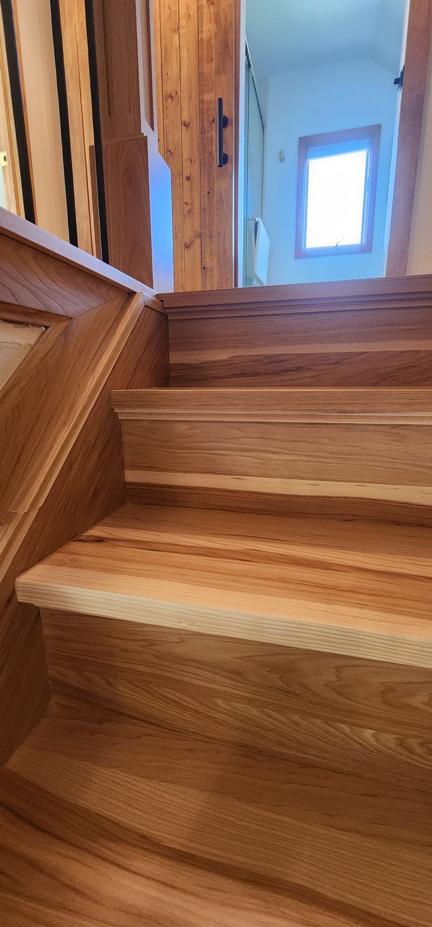 Wooden staircase with dark railing and patterned runner in a home interior