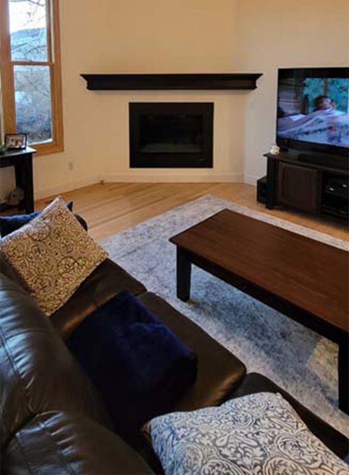 Living room with dark brown leather couch, fireplace, TV, and wooden furniture.