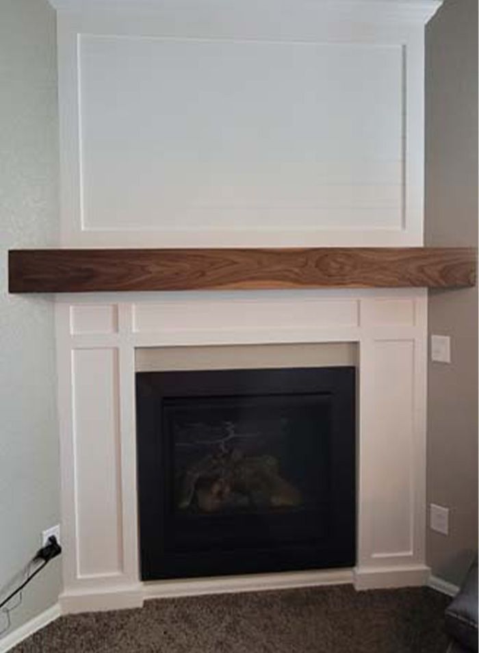 White fireplace surround with a dark wood mantel, black firebox, and a large white panel above.