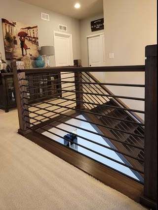 Dark wooden railing with horizontal metal bars, overlooking a staircase.