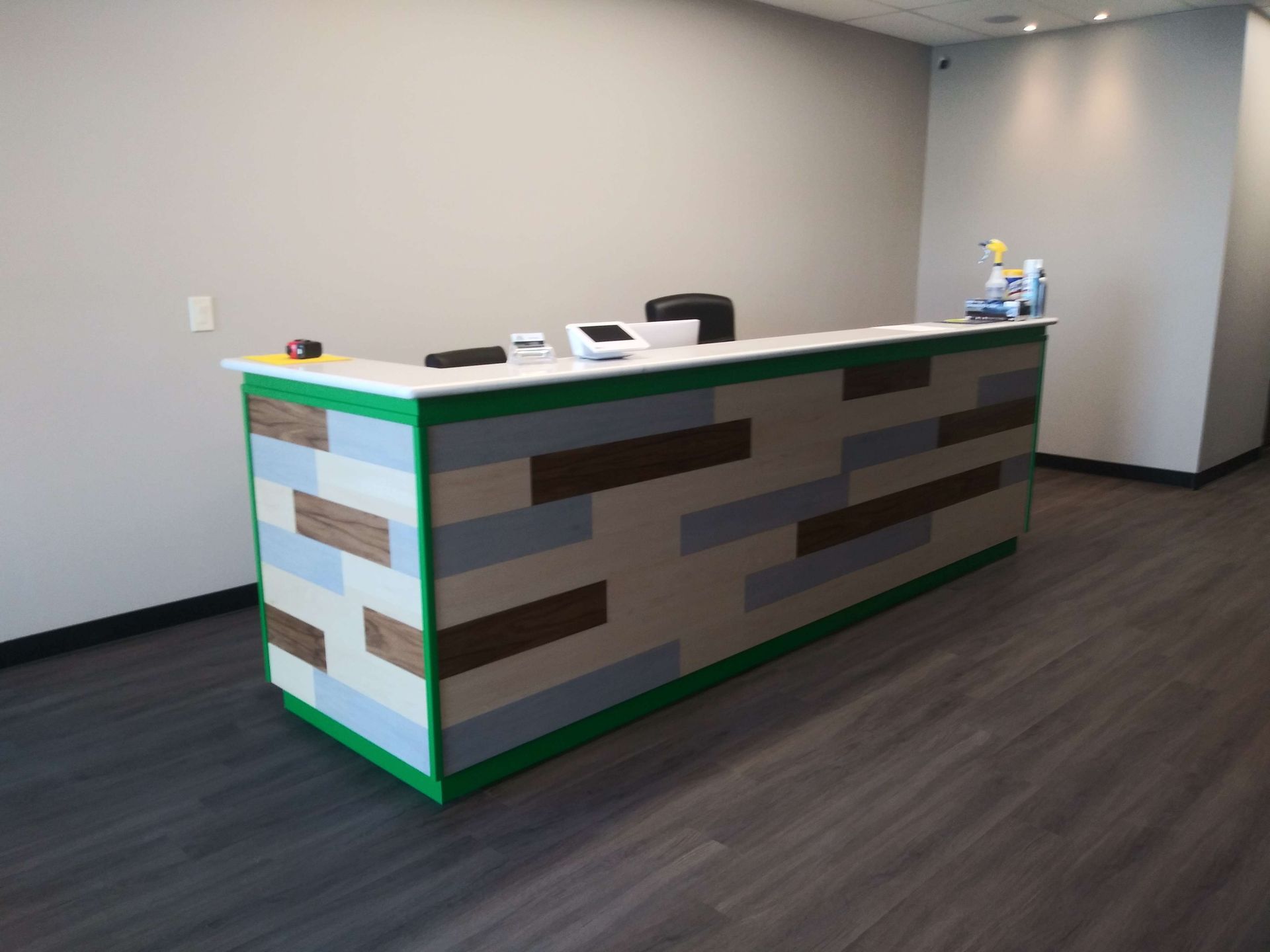 Reception desk with multi-colored wood paneling, white countertop, and green trim.