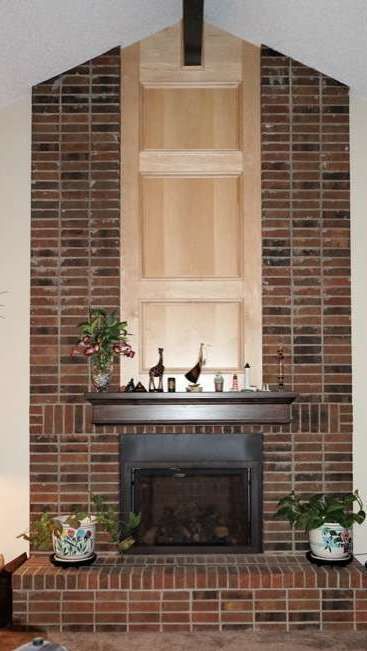 Brick fireplace with built-in shelves. Wooden mantle with decorative items, plants in pots on either side.