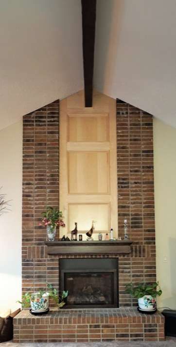 Brick fireplace with a wooden mantel, a niche, and a dark wooden beam overhead.