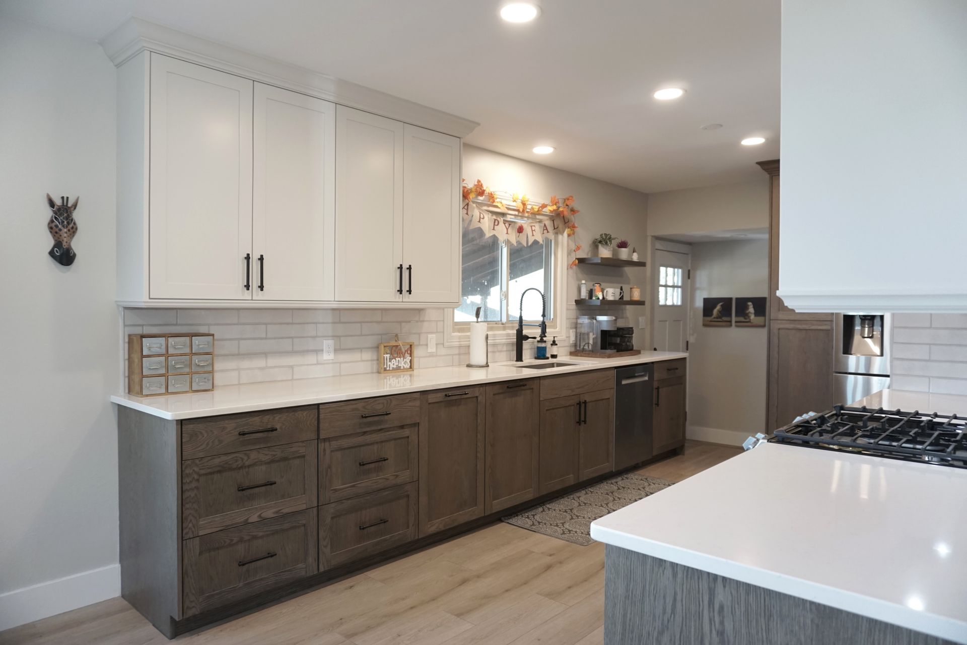 Modern kitchen with white cabinets, dark lower cabinets, white countertops, and stainless steel appliances