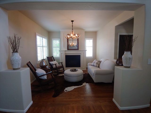 Living room with fireplace, white walls, wooden floors, and modern furniture.