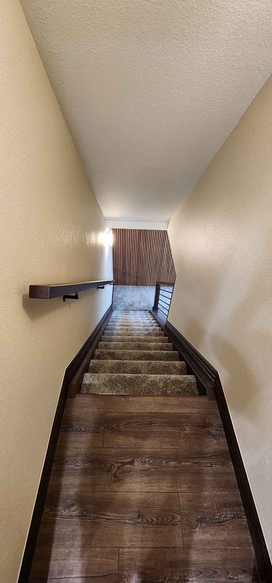 Narrow hallway with stairs leading to a bright doorway and striped curtain at the end