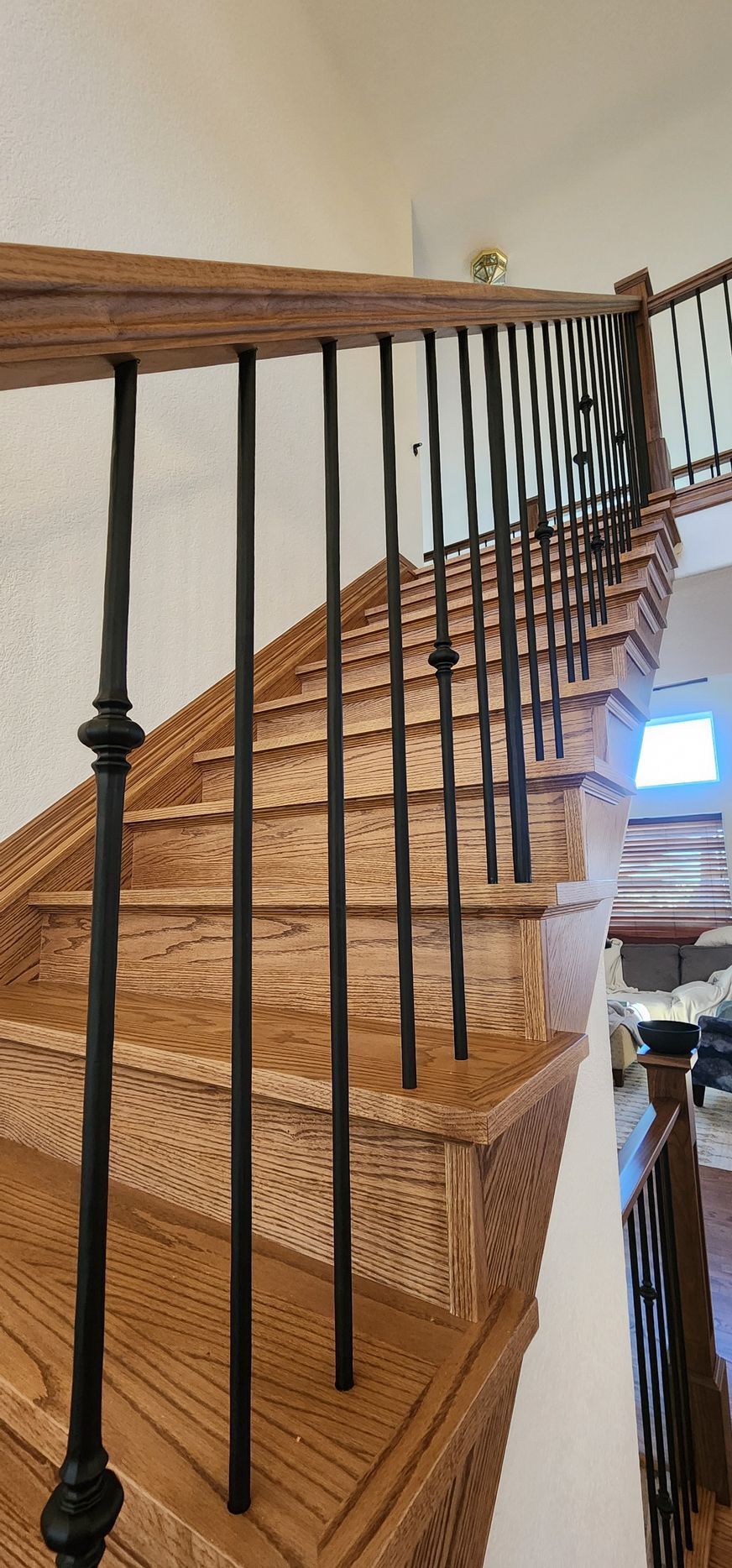 Wooden staircase with black metal balusters.