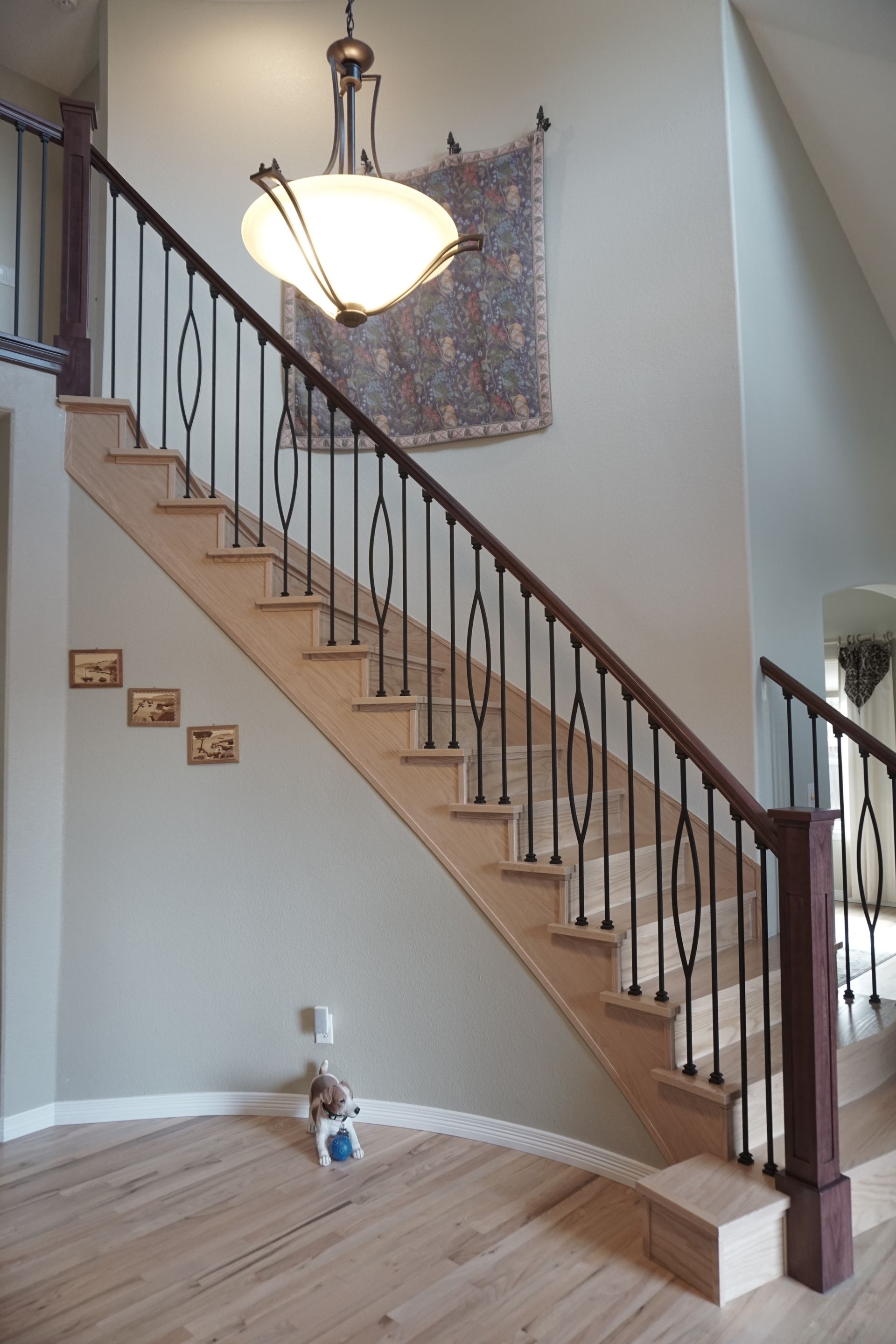 Staircase with light wood steps and dark metal railings against a light green wall.