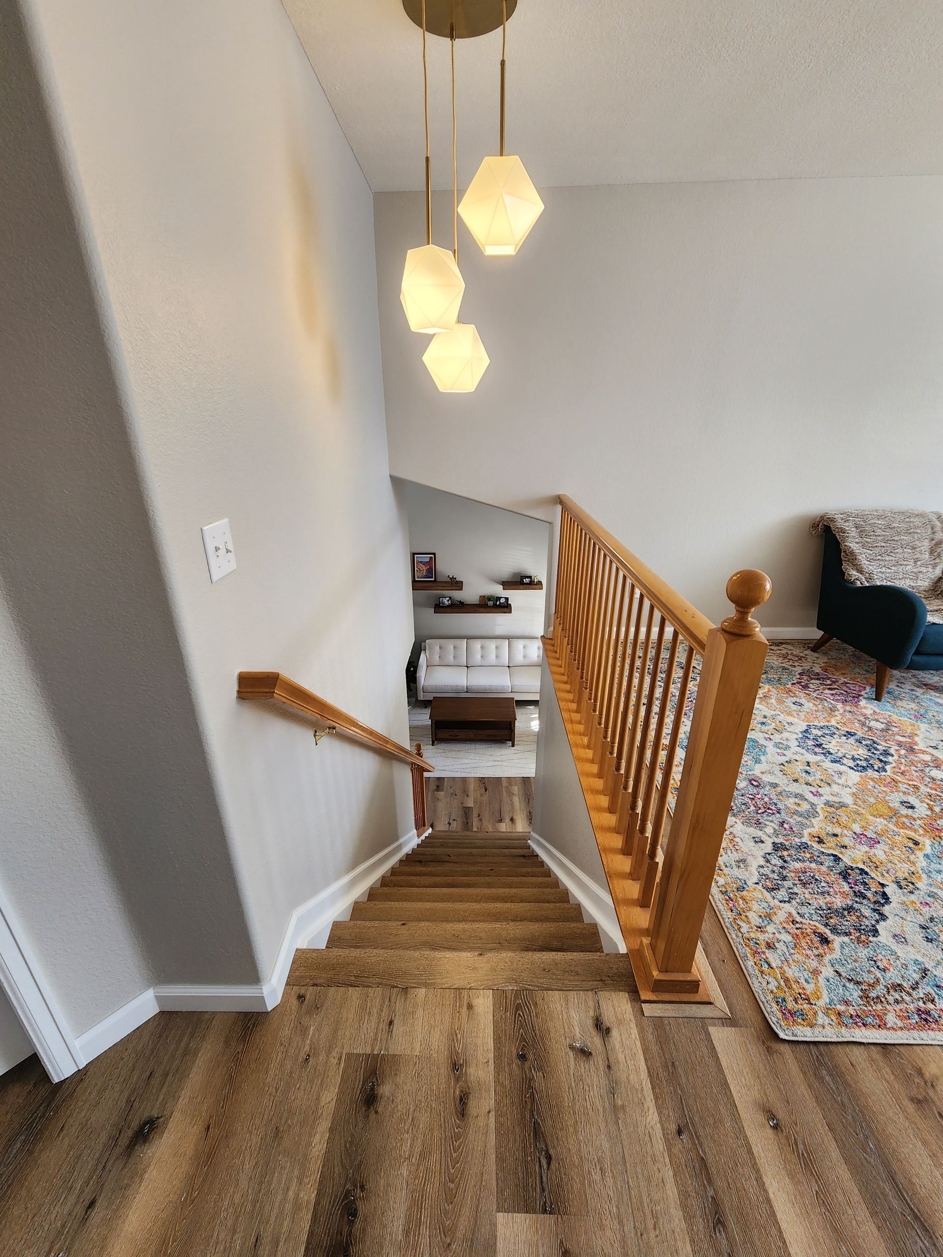Staircase with wood steps and railing, light fixture, view of living room.
