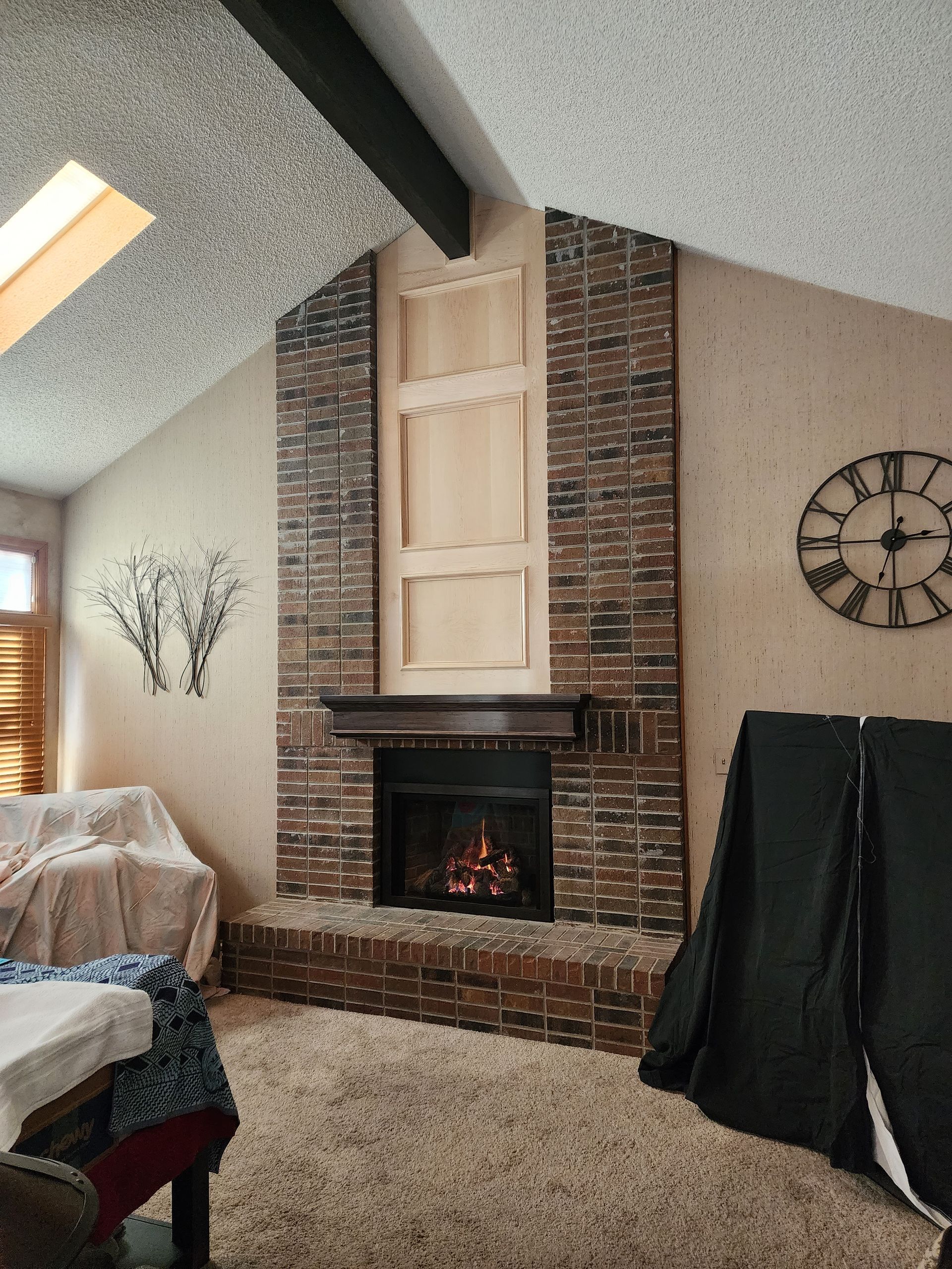 Brick fireplace in living room with built-in wooden frames. Brown carpet and beige walls.