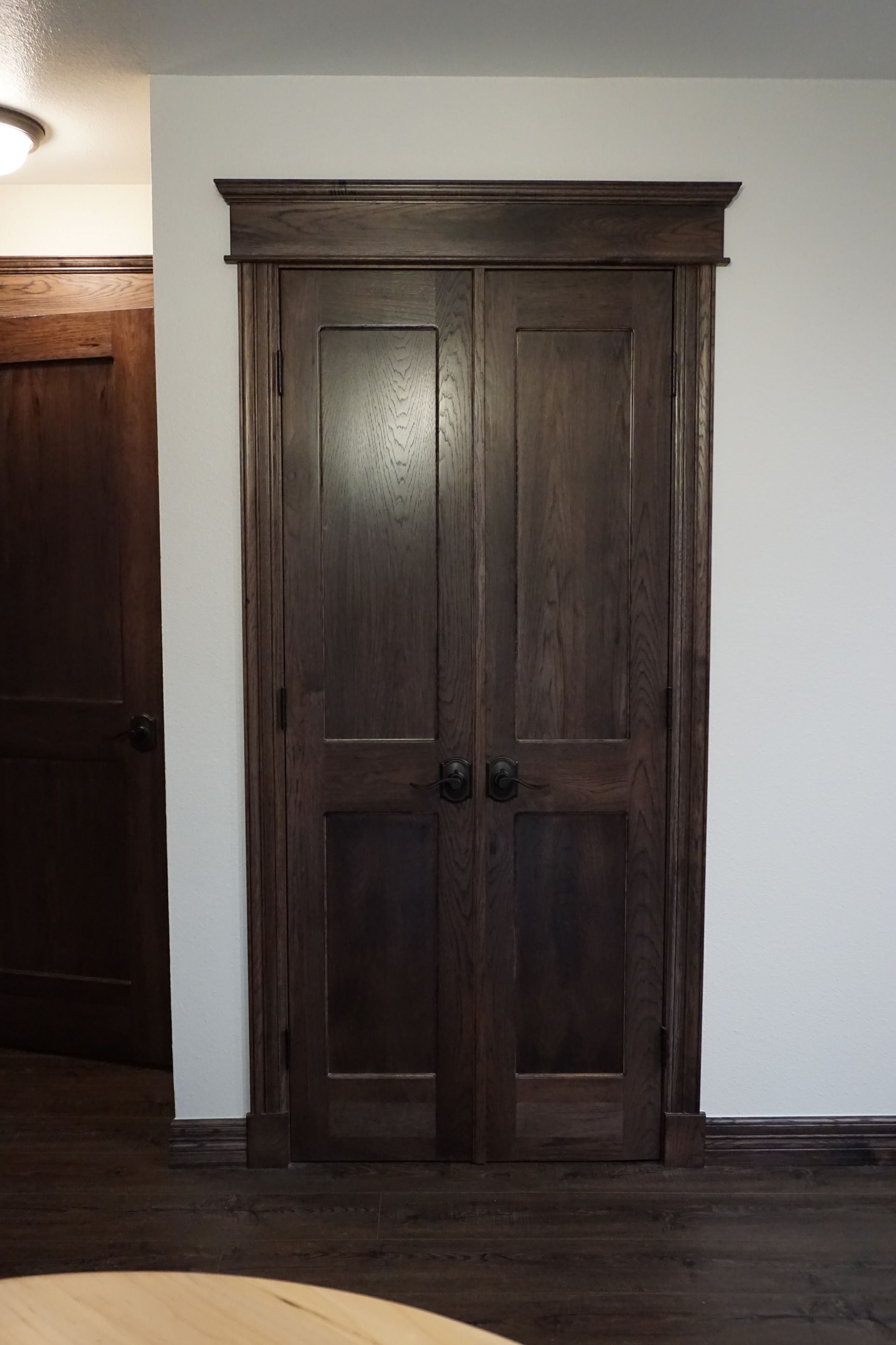 Dark wooden double doors with ornate trim and hardware set against white walls.
