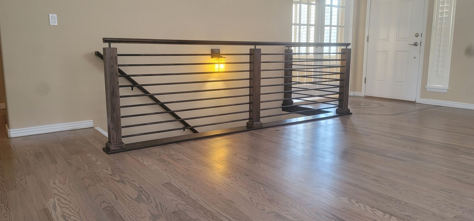 Wooden railing with horizontal bars on a wood floor. A light shines in the center.