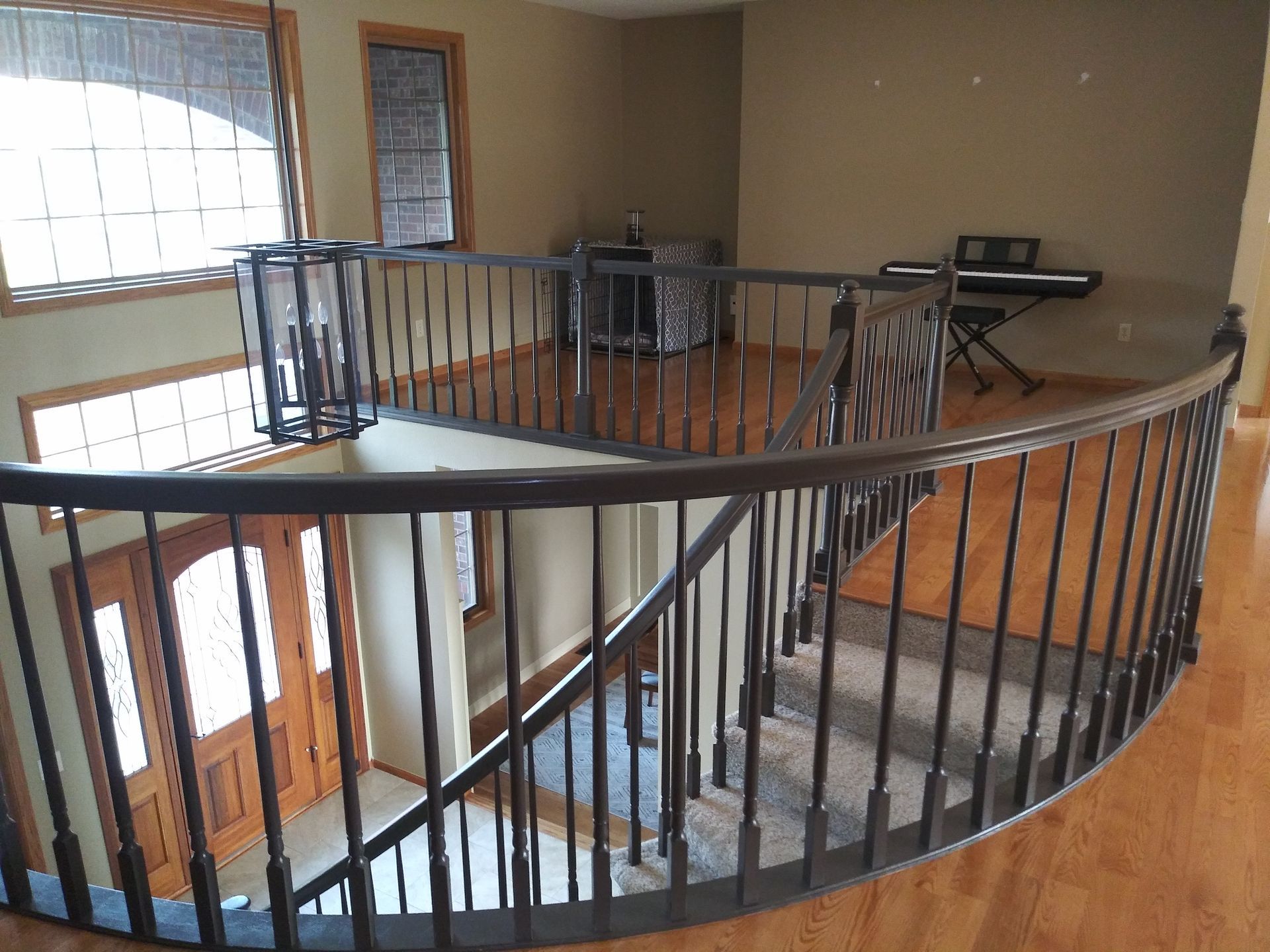 A two-story interior with a curved staircase, hardwood floors, and a dark wooden railing.