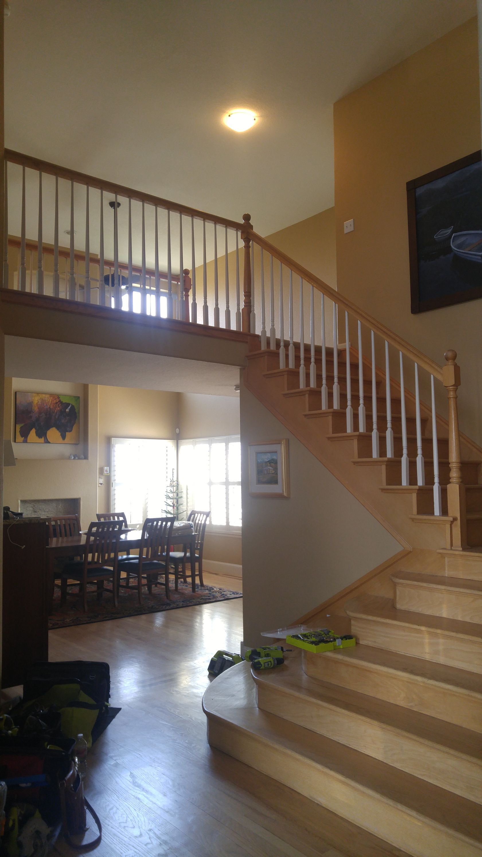 Two-story entryway with a staircase leading up to a balcony; a dining area is visible below.