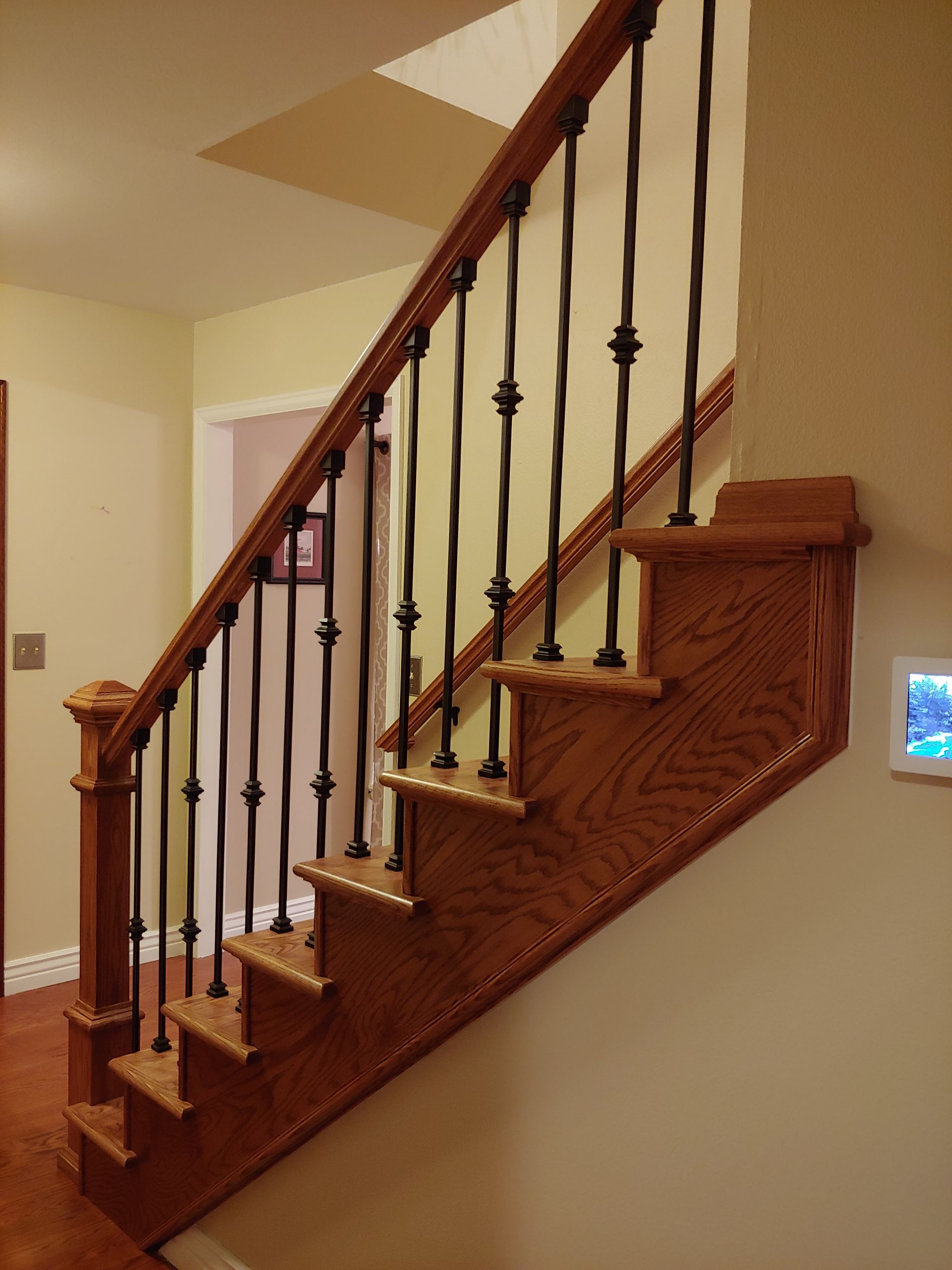 Wooden staircase with black metal balusters and a wood handrail.