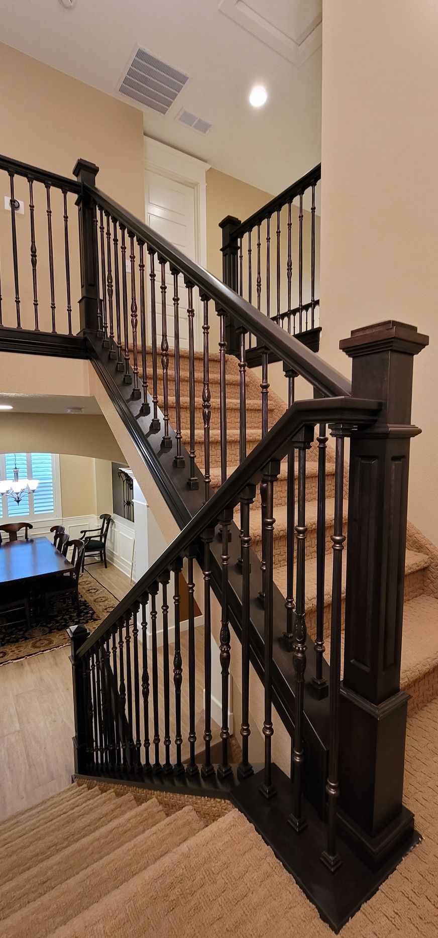 A dark wooden staircase with brown carpet and white walls.