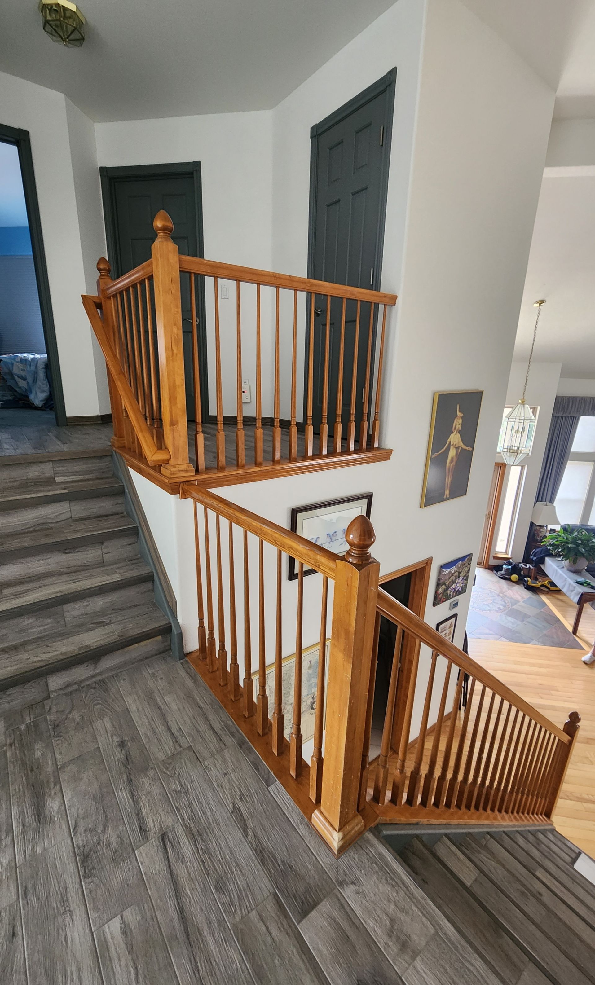 Wooden staircase with light brown handrails and gray flooring.