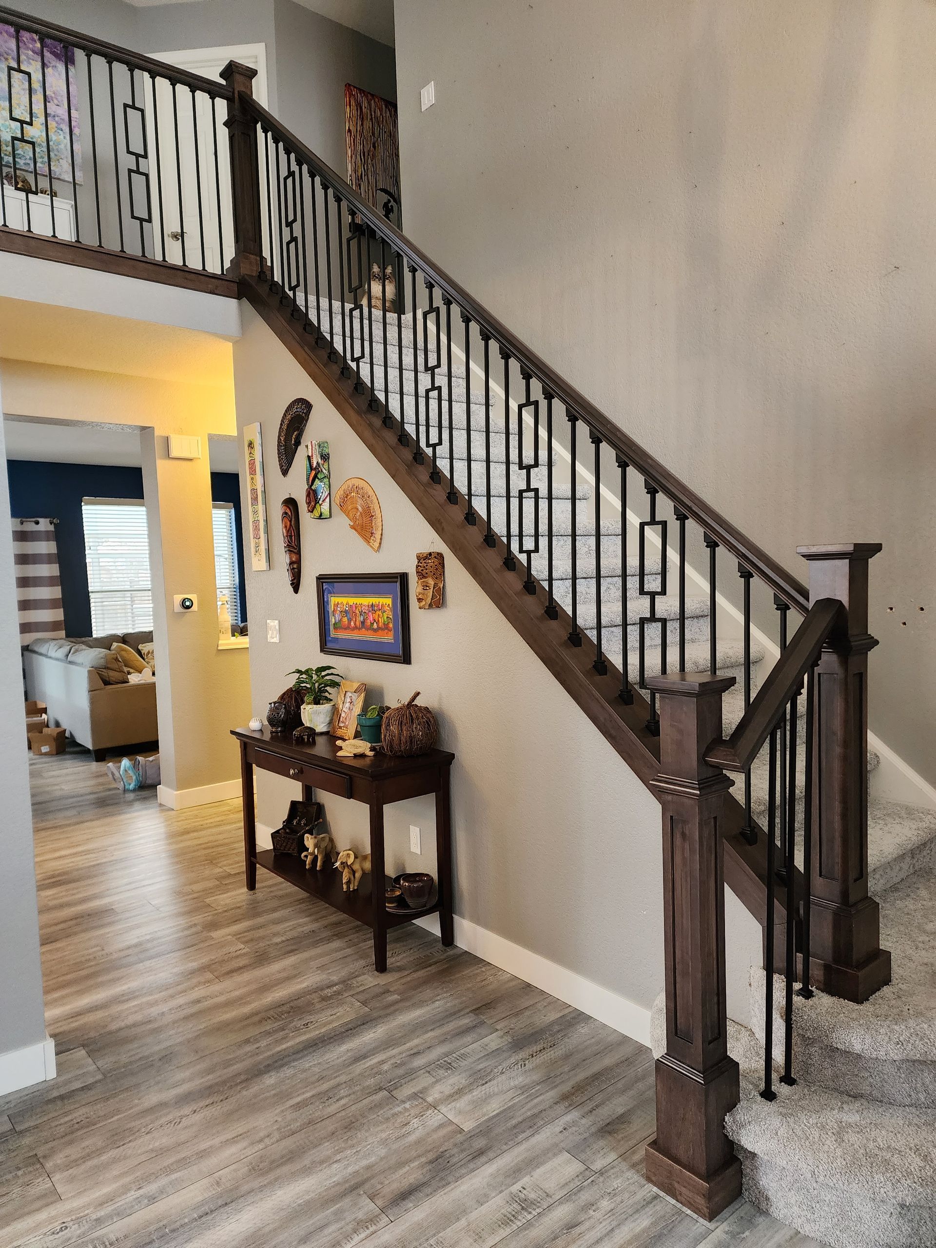 Wooden staircase with decorative metal railing and dark brown newel posts in a home.