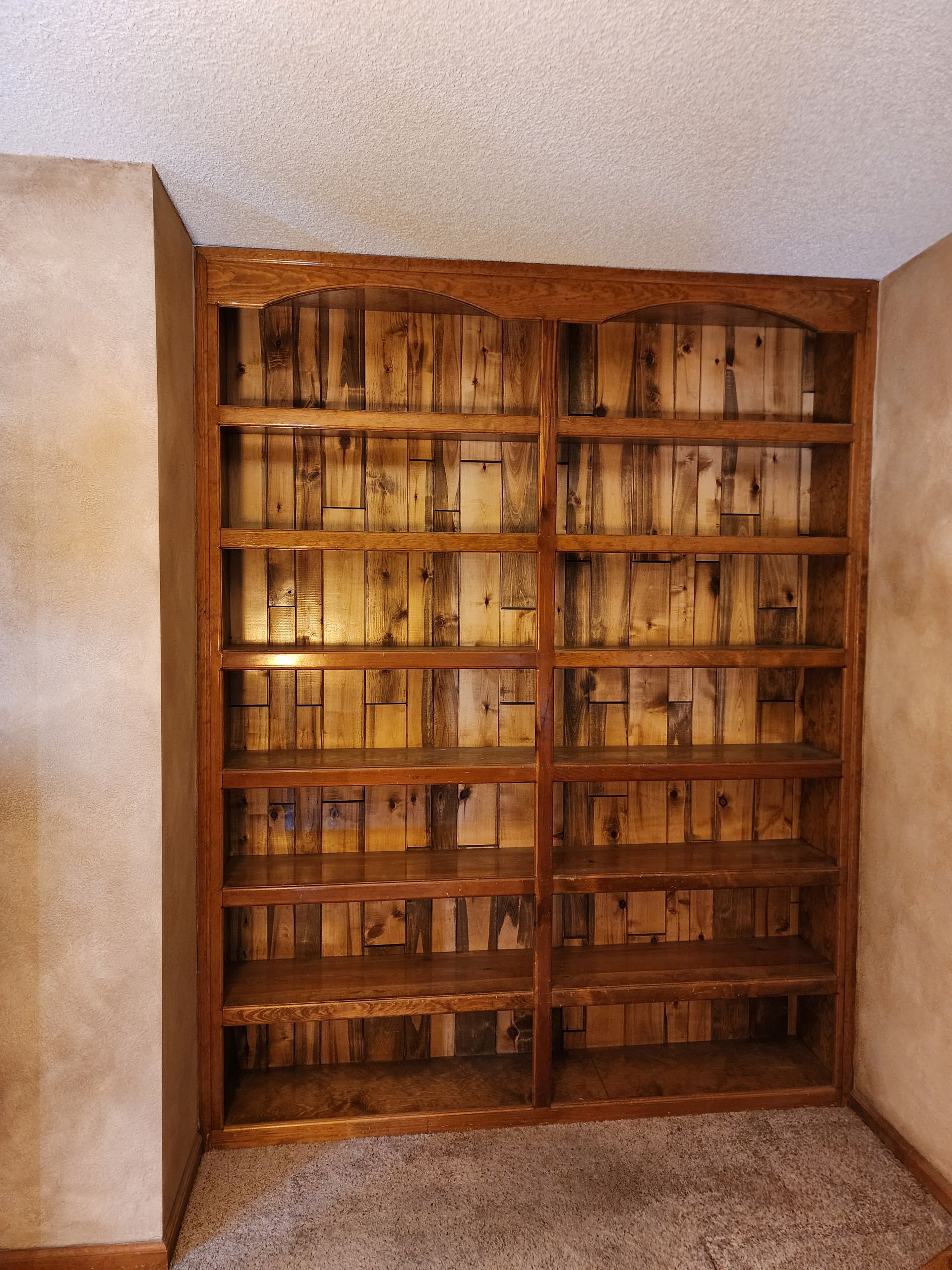 Two wooden bookshelves built into the wall, with dark wood finish and carpeted floor.