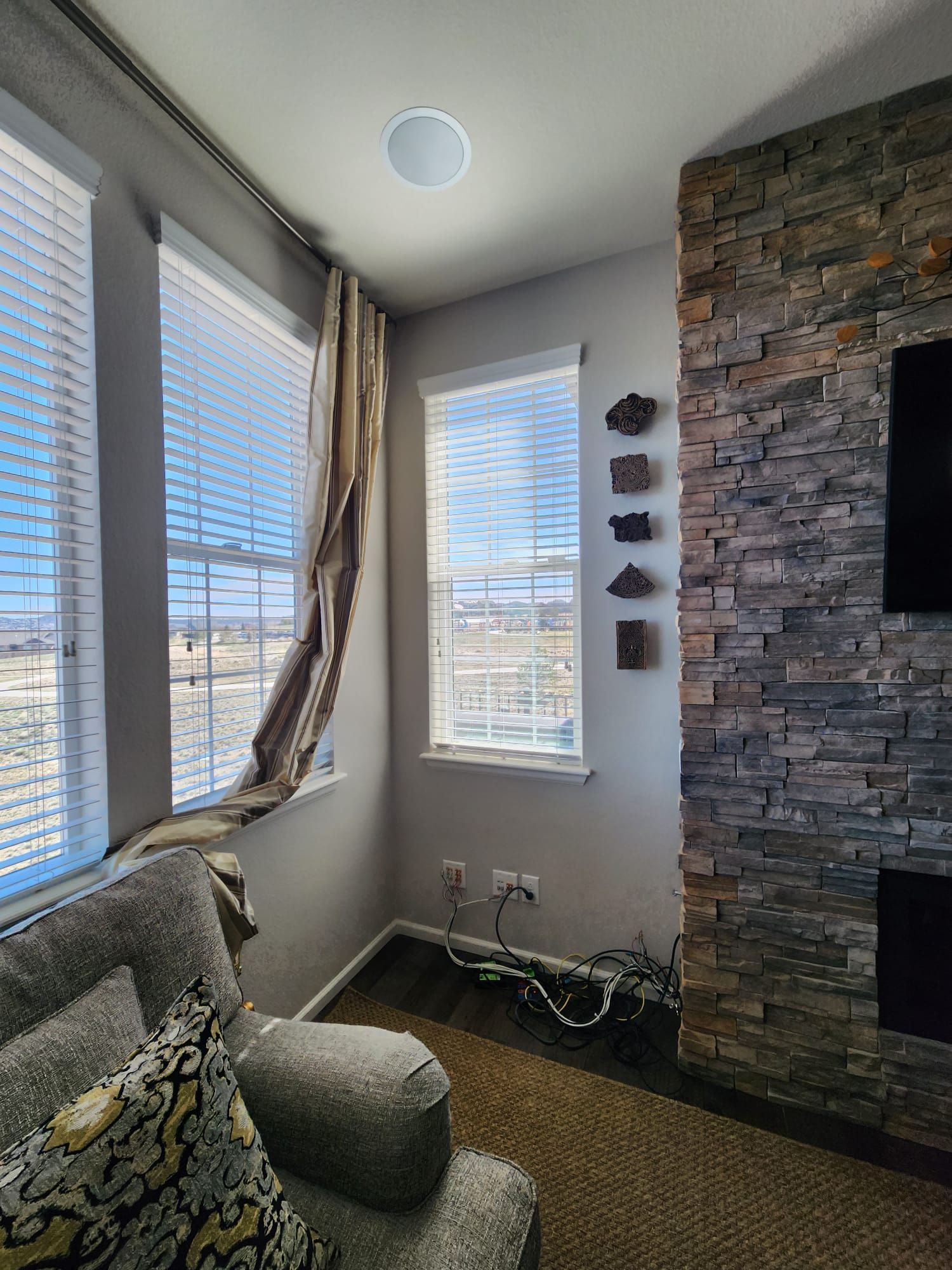 Cozy living space with stone fireplace, windows, and armchair.