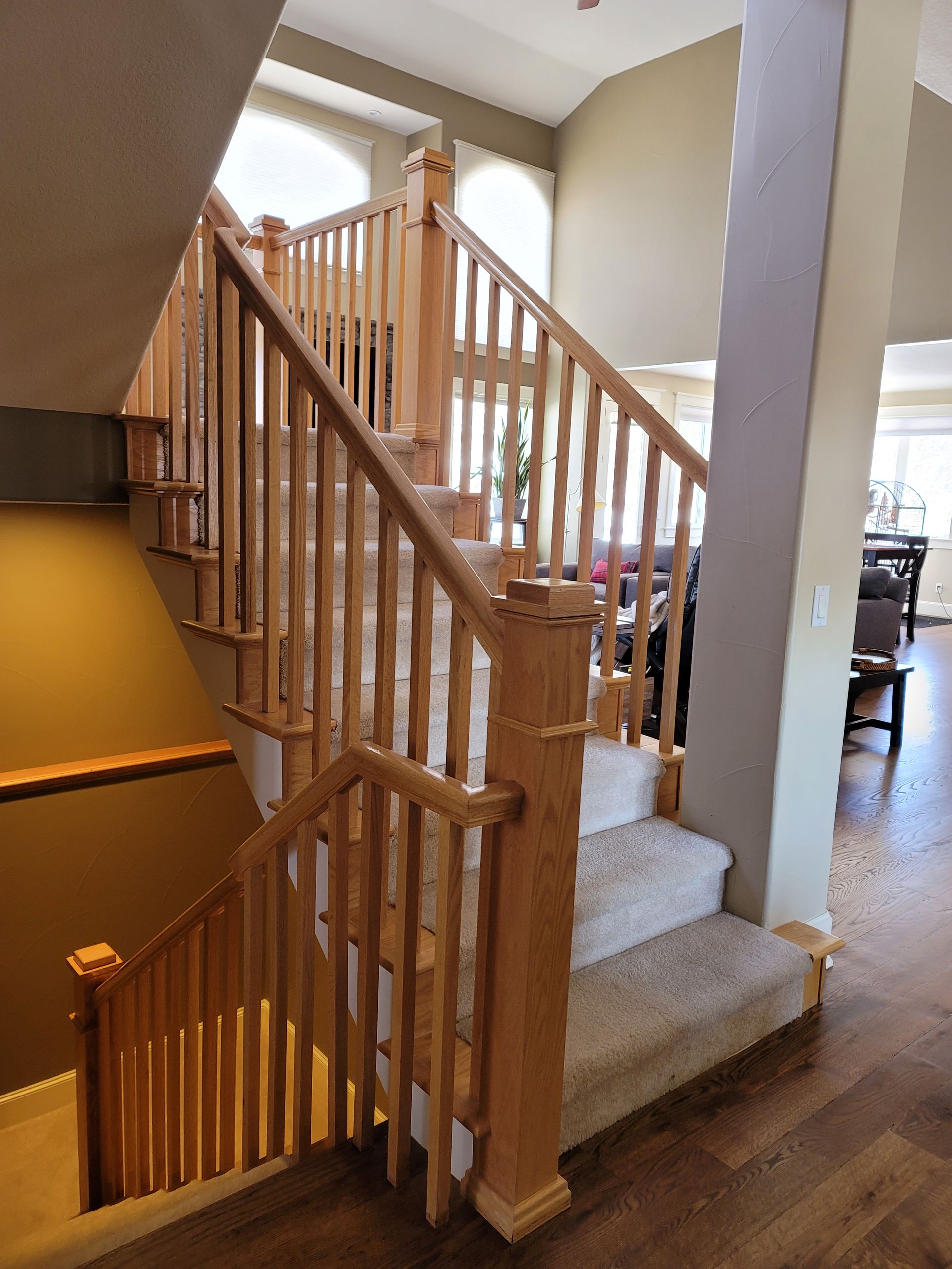 Wooden staircase with light-colored carpeted steps and railing in a home.