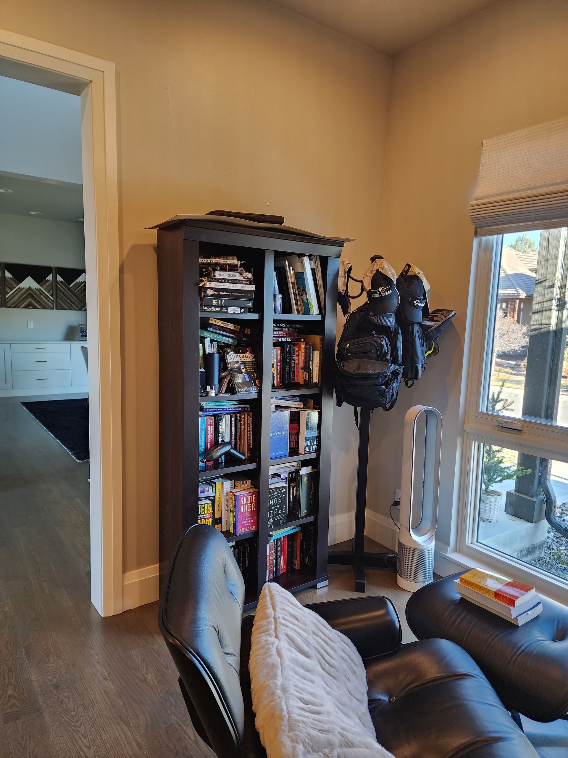 Bookshelf with books and decorative items, next to a recliner chair near a window.