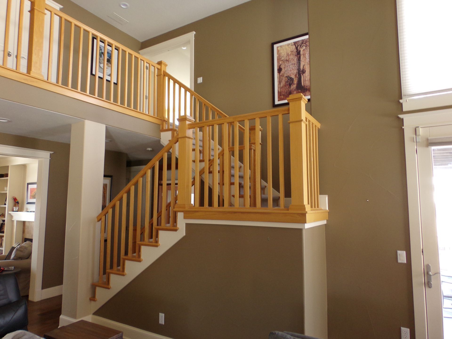 Wooden staircase with railing in a home, against brown wall. Upper level visible.