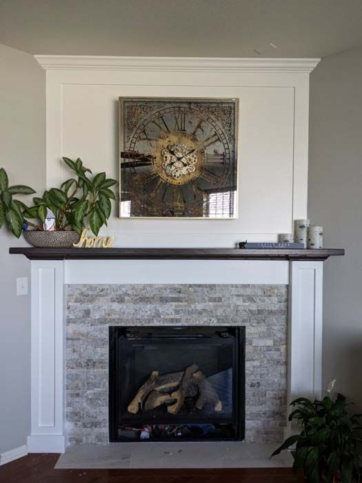 Fireplace with light brick facing, dark wood mantle, and clock art.