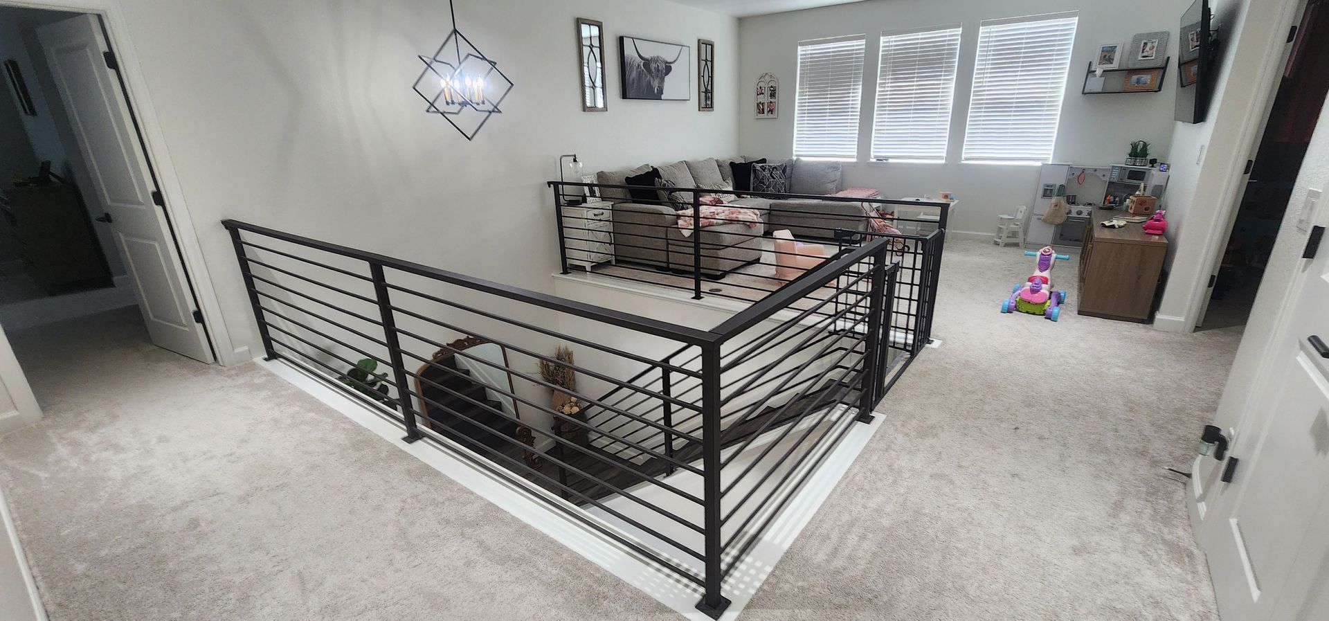 Living room with black metal pet pen, dog crate, sofa, and wall decor near a window with blinds