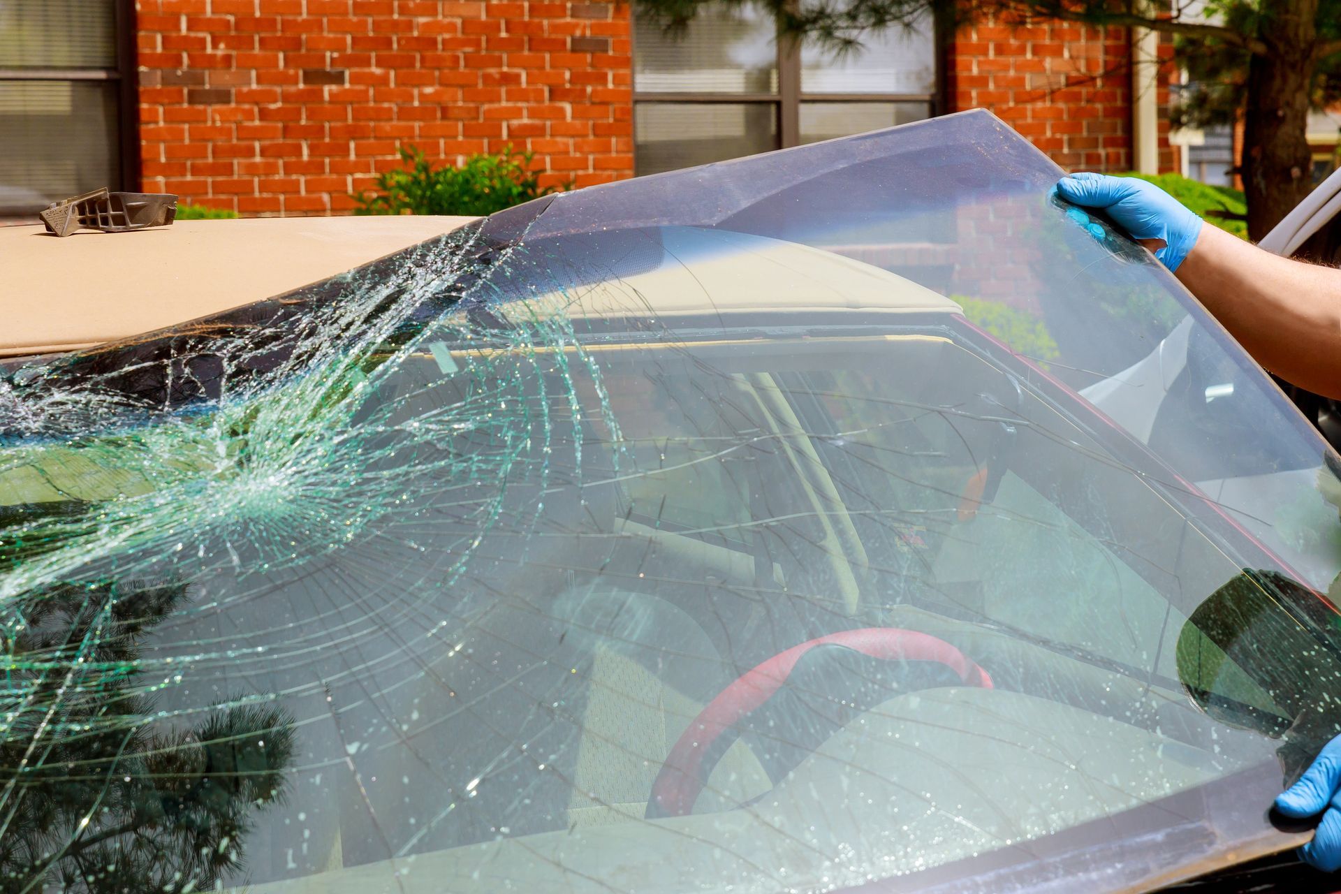 Workers remove the crashed windshield of a car. Workers remove the crashed windshield of a car.