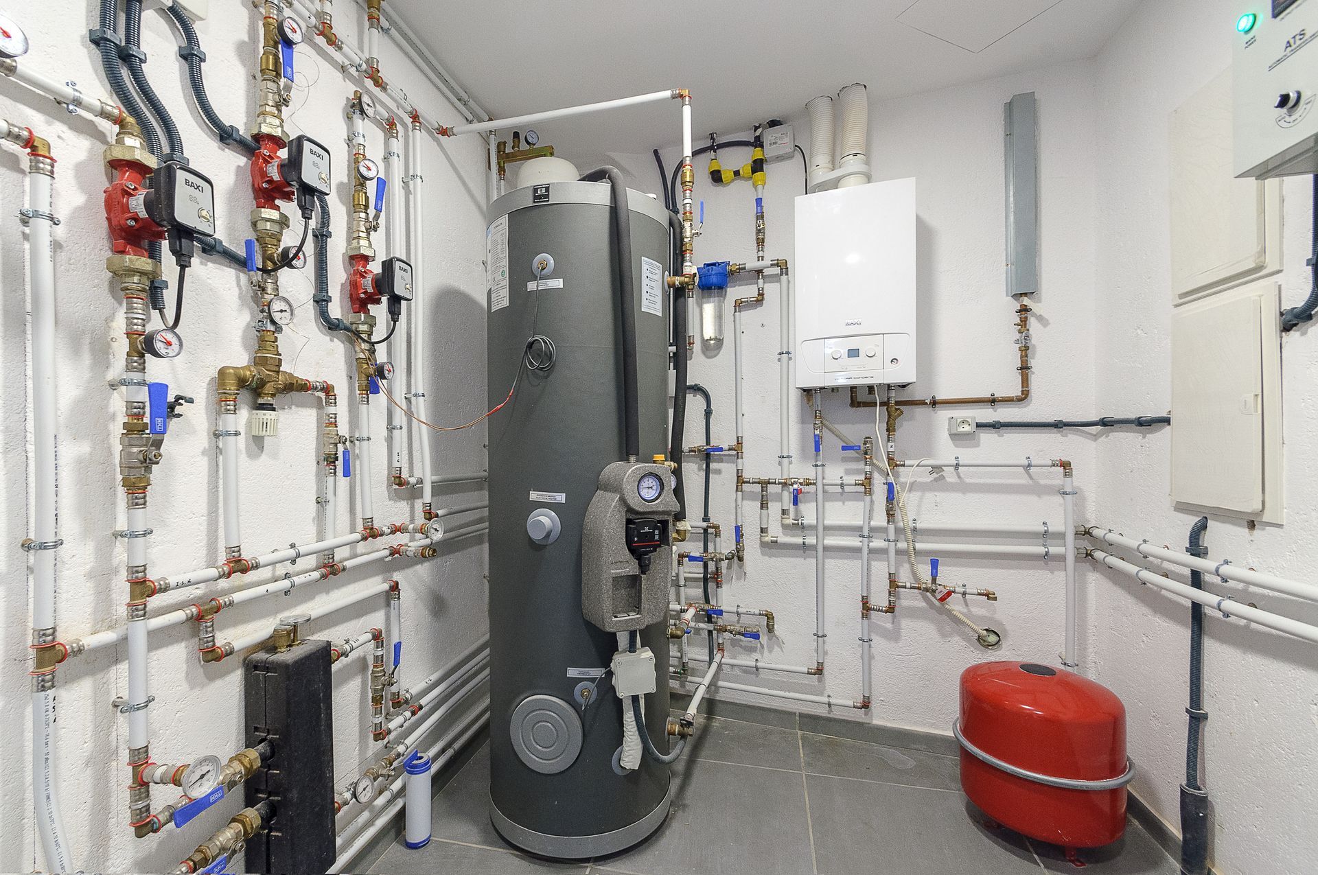 A room filled with lots of pipes and a boiler.