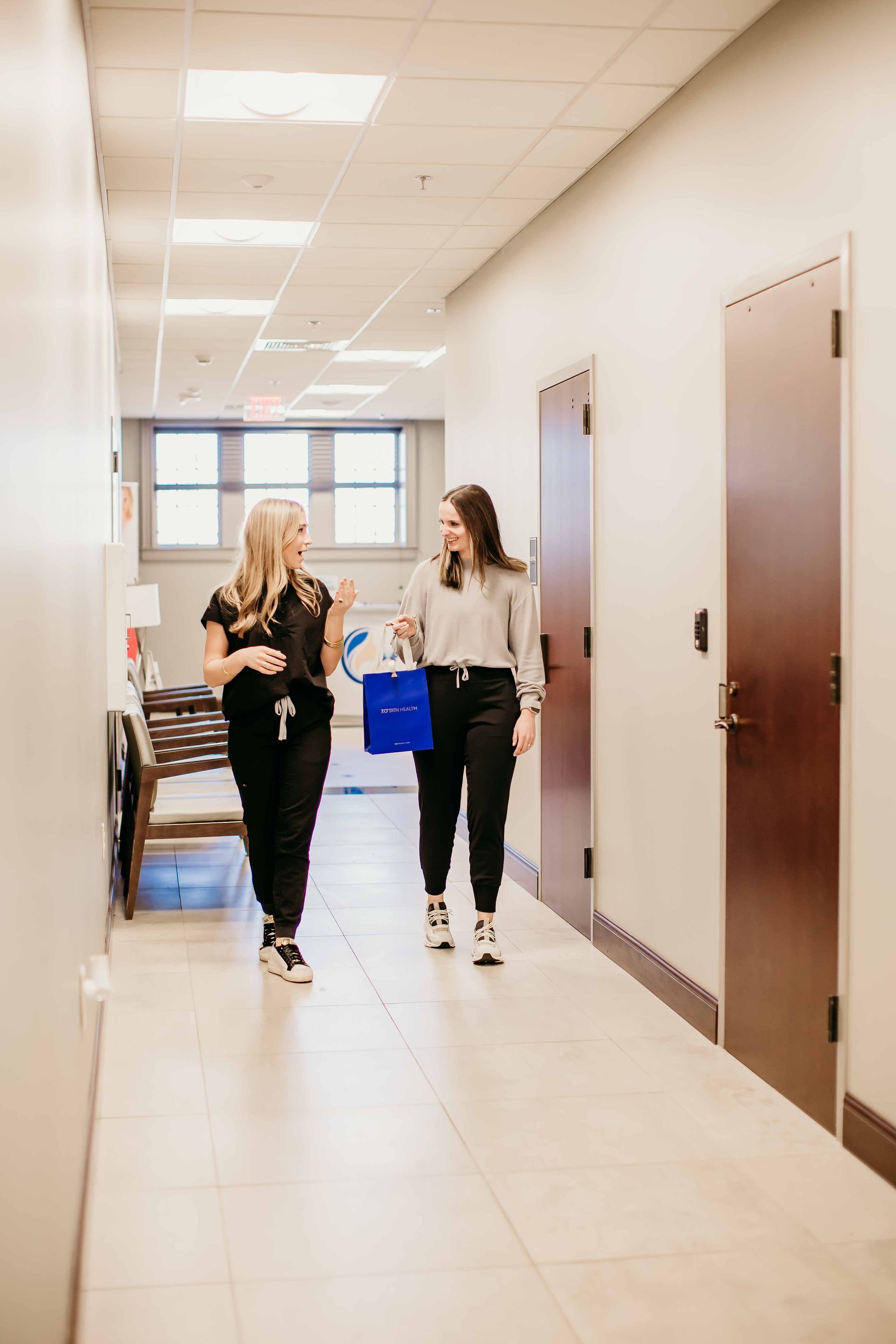 Two women are walking down a hallway in a hospital.