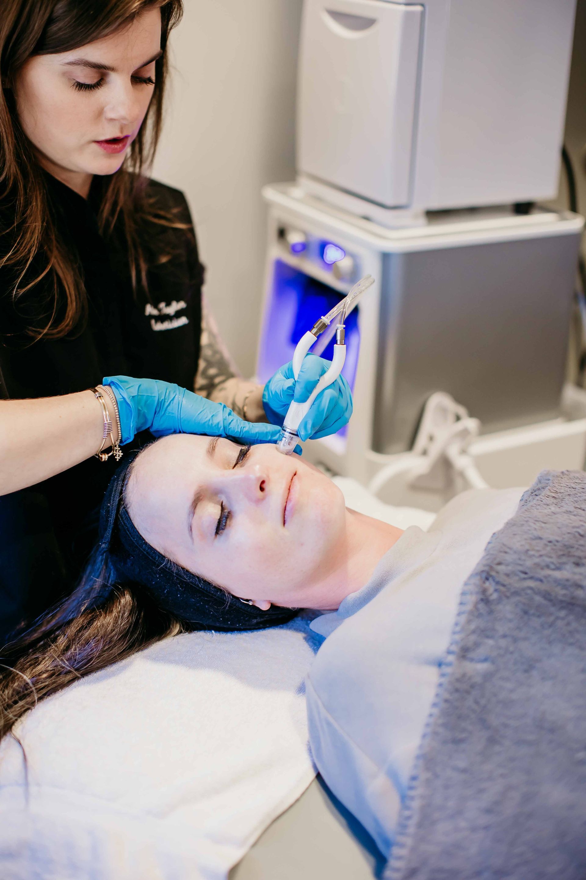 A woman is laying on a bed getting a treatment on her face.