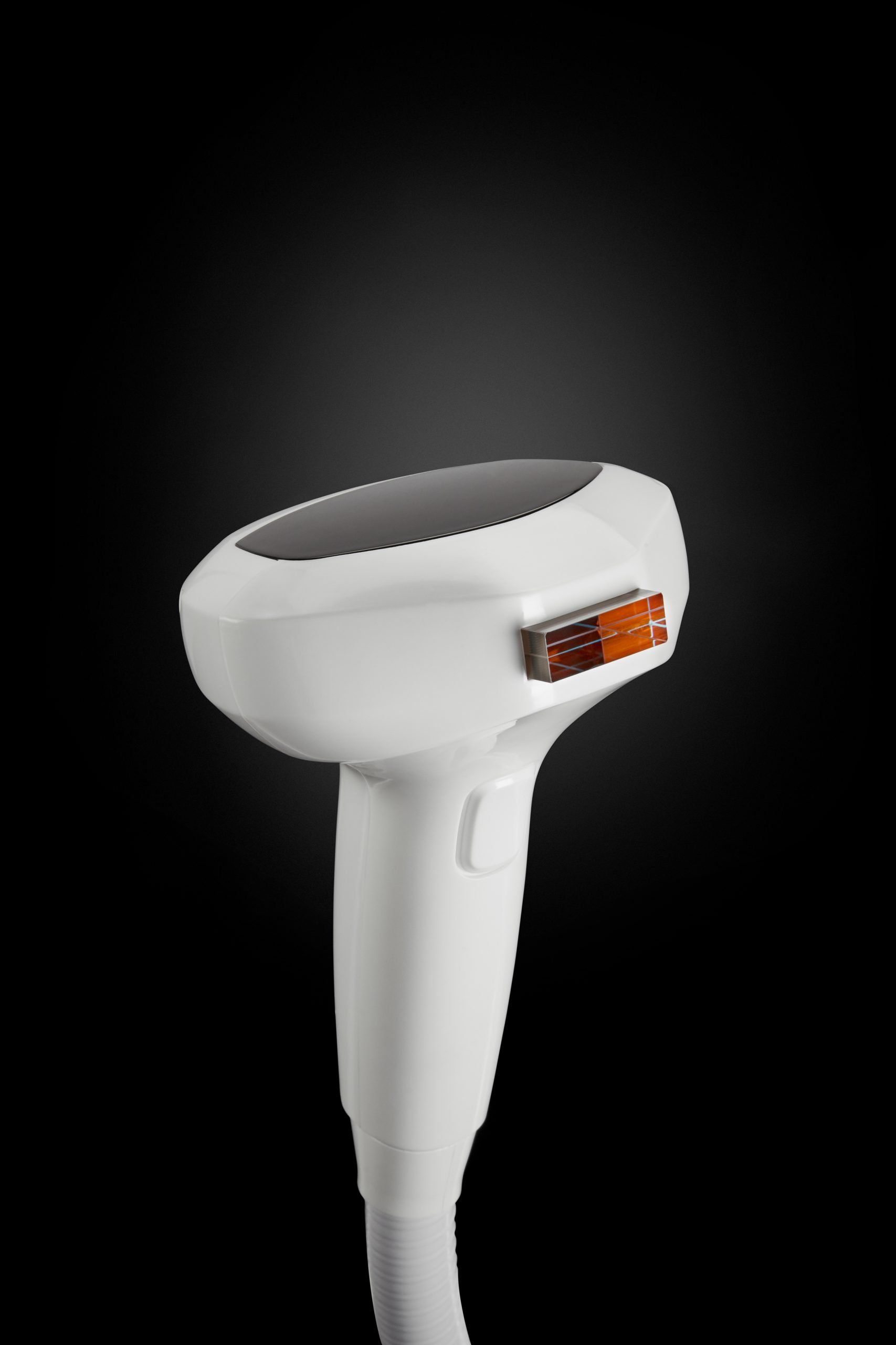 A close up of a white hair removal device on a black background.