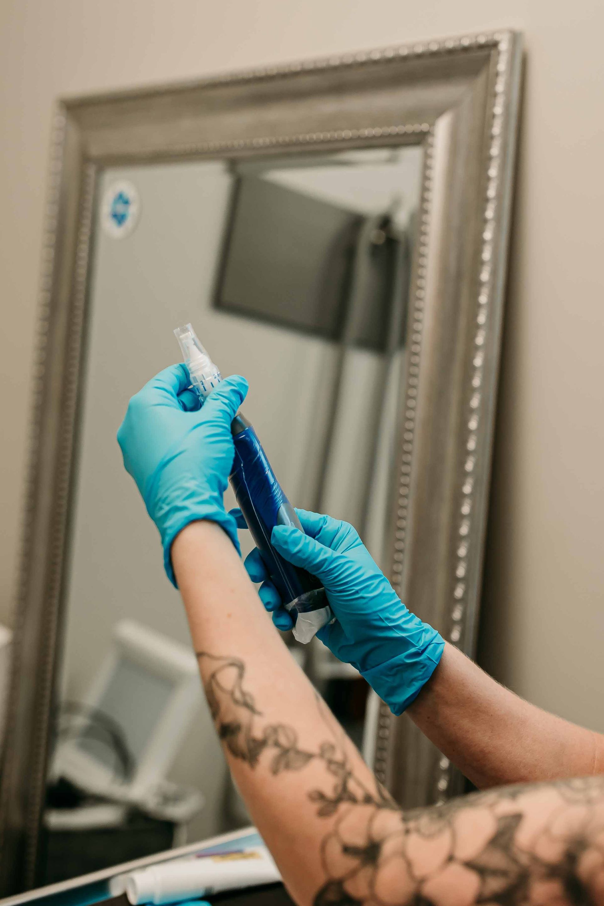 Gloved hands trimming hair with electric clippers near a mirror in a salon