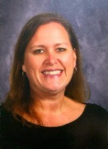 A woman in a black shirt is smiling for the camera.