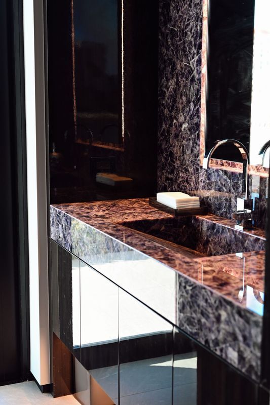 Modern bathroom vanity with dark marble countertop, sink, and mirror reflection