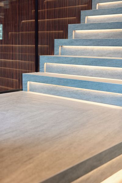 Modern indoor staircase with white steps, blue risers, and wood-paneled walls