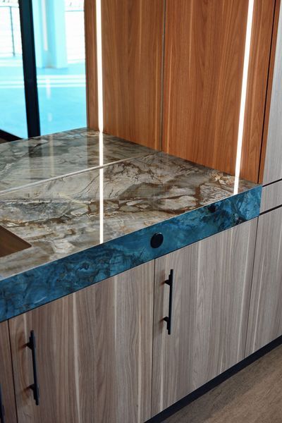 Marble-topped wood cabinet with blue trim and a black drawer pull in a modern interior
