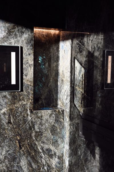 Dim hallway with dark marble walls and lit wall panels in a modern interior.