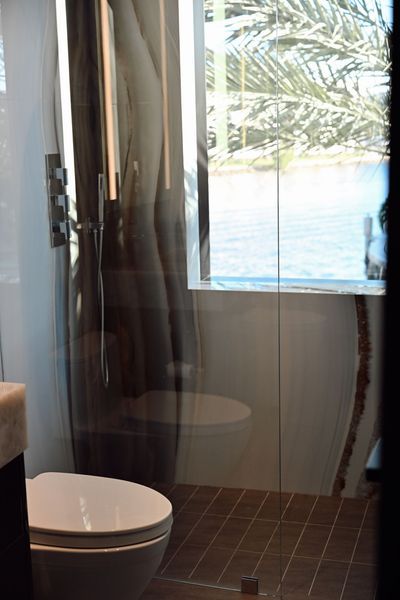 Modern bathroom with glass shower, white toilet, and ocean view through the window