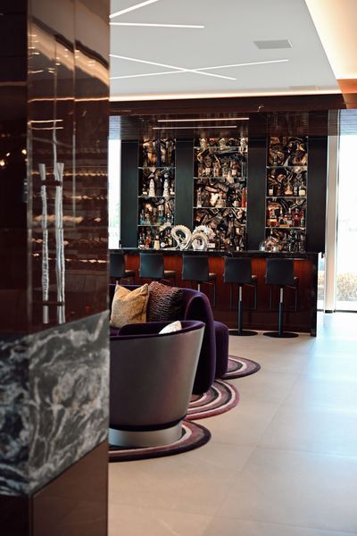 Modern hotel lounge with purple chairs, marble columns, and a bar display in the background