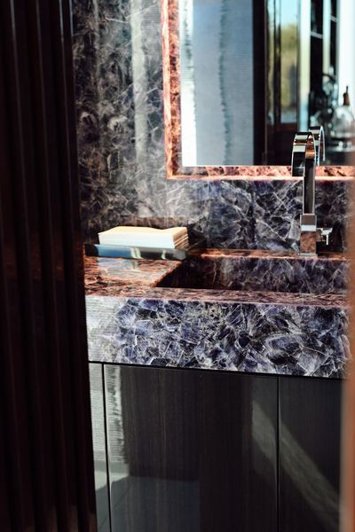 Marble bathroom vanity with sink and mirror beside a dark wood cabinet
